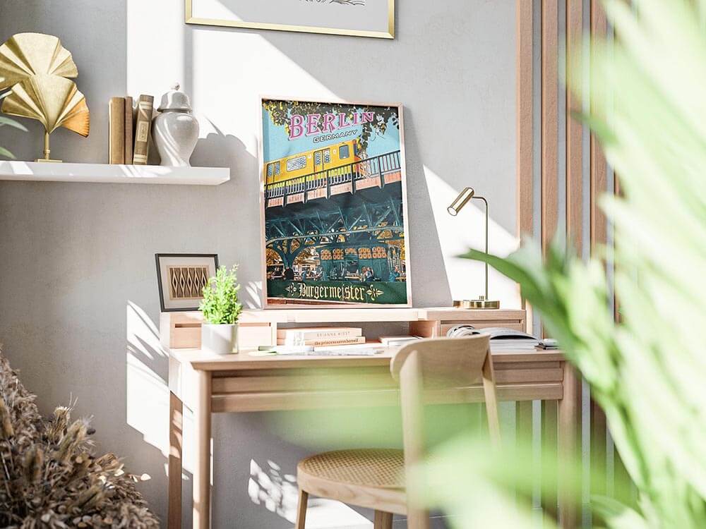 Retro Berlin U-Bahn print resting on a sunlit oak desk beside a brass lamp and small potted plant