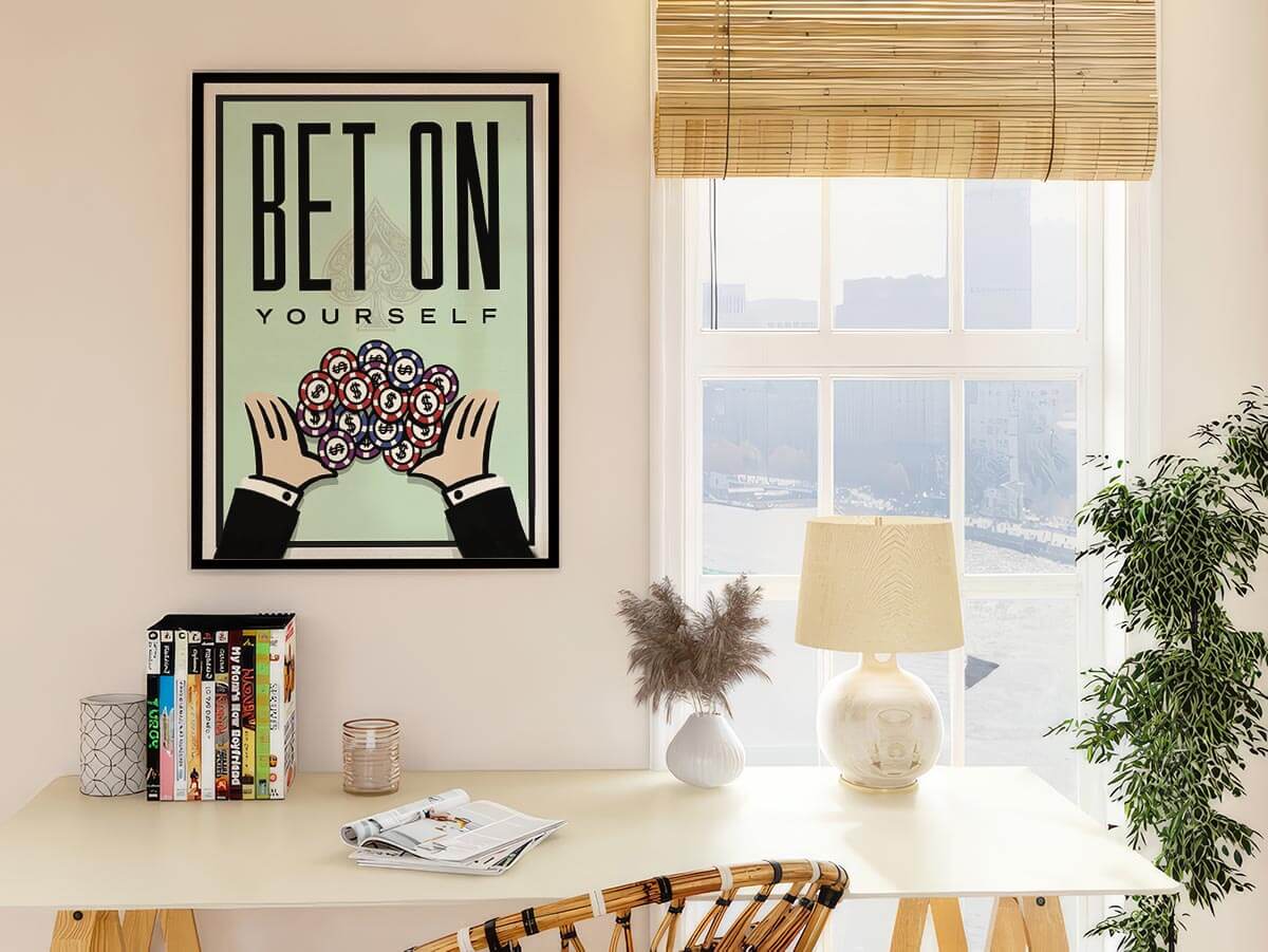 Bet On Yourself poker poster on a warm white wall beside a sunlit study desk with books