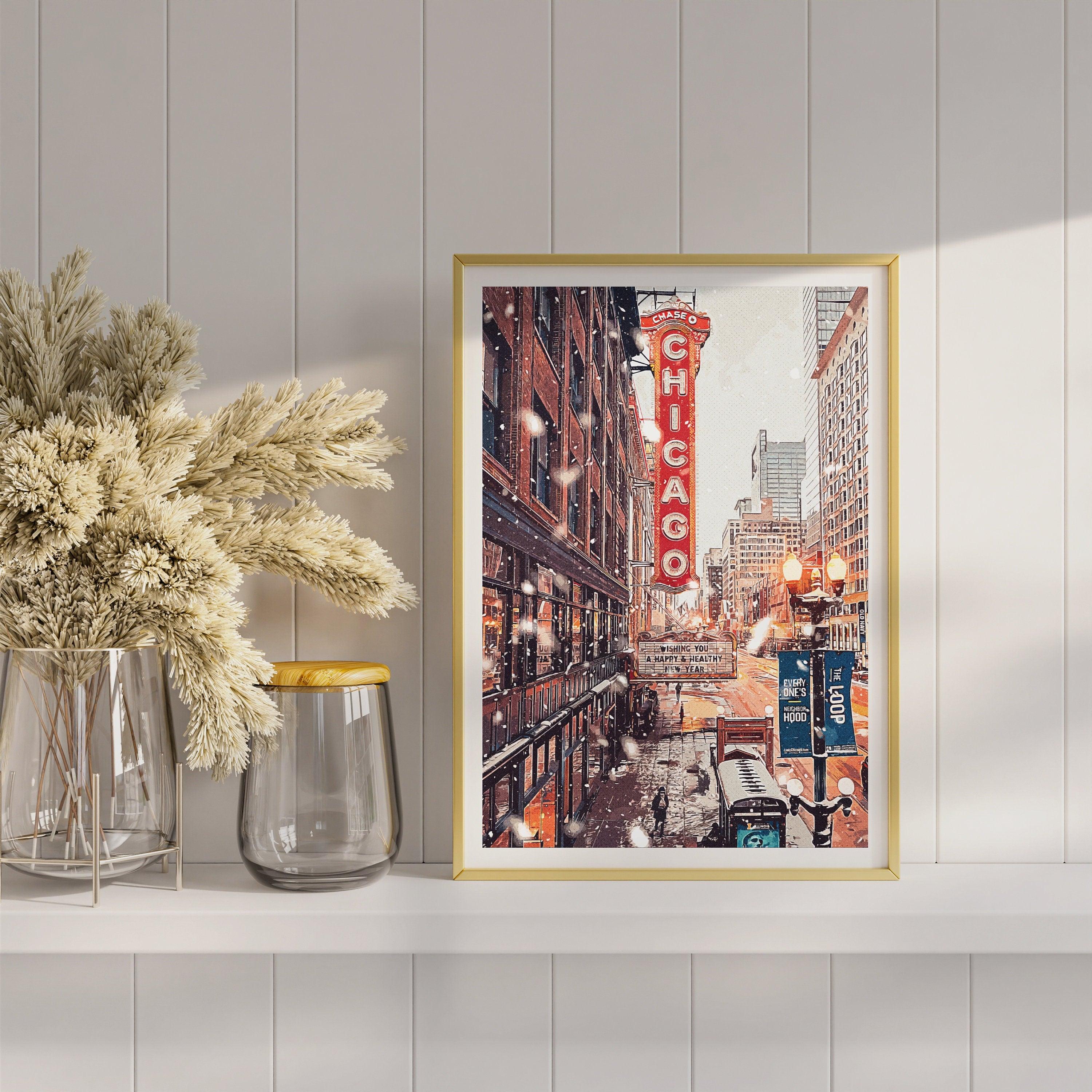 Gold framed Chicago Theatre winter print on a shelf with dried pampas and glass vases