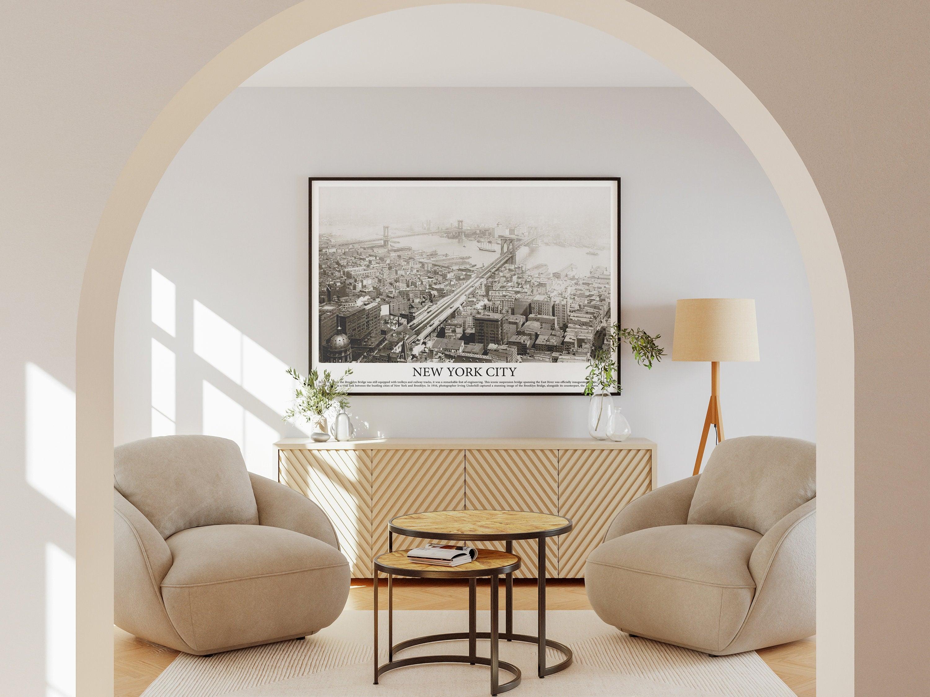 Black framed New York City aerial print with caption text, seen through an arch in a minimal beige room